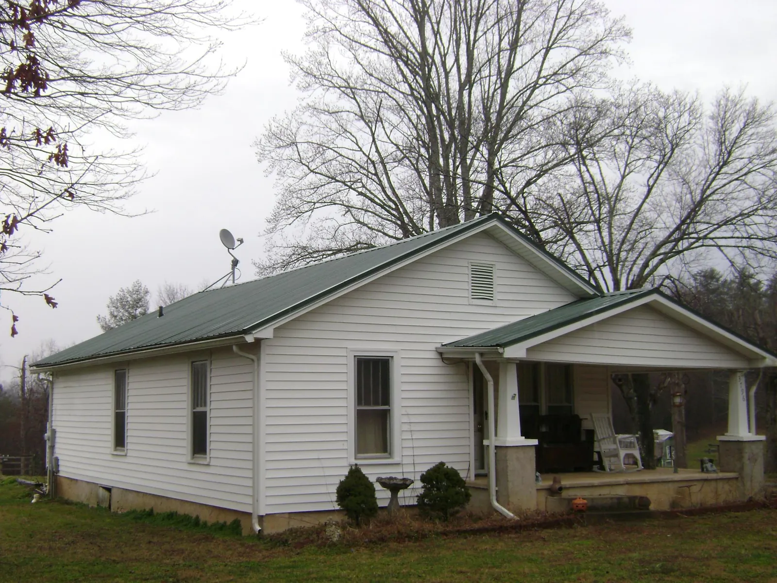 Green metal roof on a white bungalow with a side porch in Little York